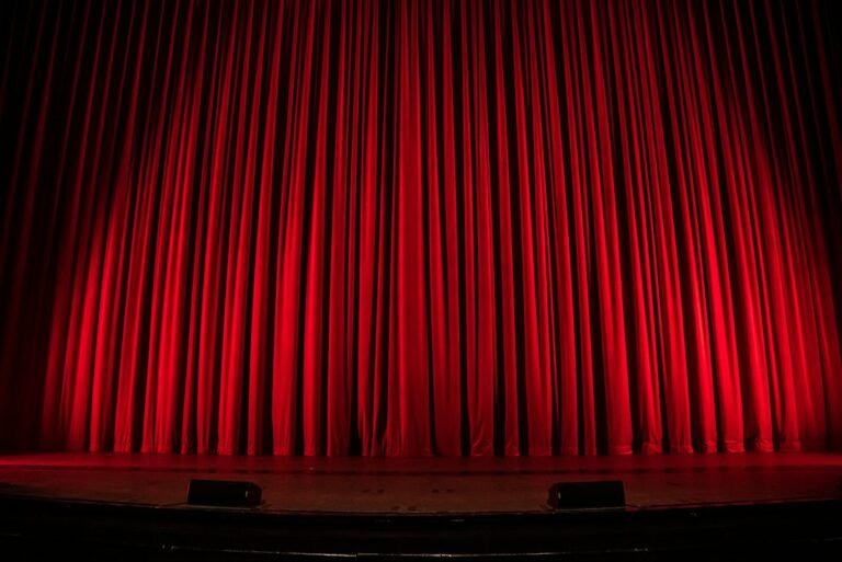 Illuminated theatre stage with red curtain