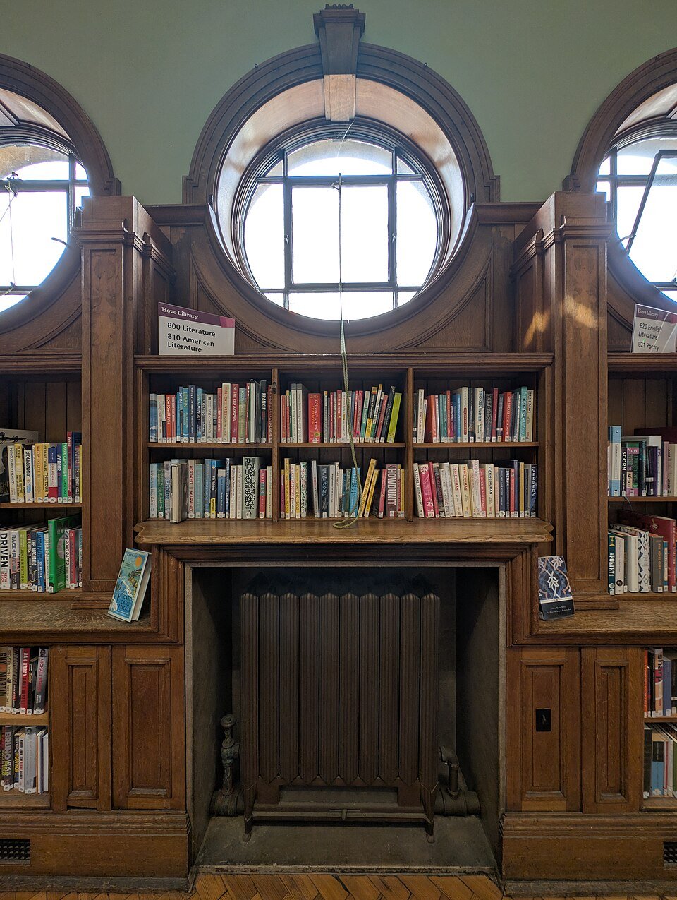 Bookshelves beneath a circular window inside Hove Library on Church Road, photographed in August 2025